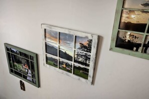 A wall with three framed windows displaying different landscapes.