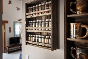 A wooden spice rack with multiple glass jars containing various spices. - Lakefront w Water Toys, Deck, Fire Pit & Grill (Springfield)
