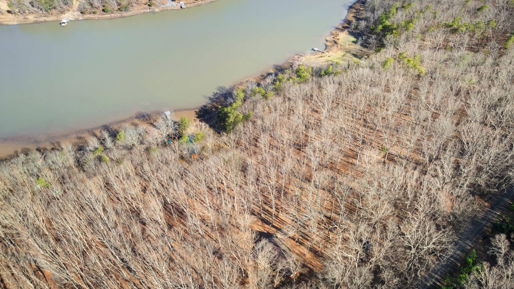 A dry, barren landscape with sparse vegetation and a body of water.