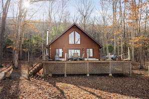 Une cabane dotée d’une terrasse, de grandes fenêtres et d’un escalier menant à celle-ci.