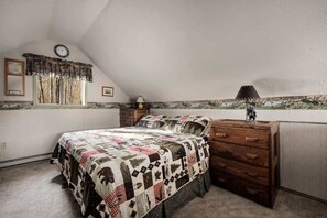 Ein Schlafzimmer mit einem Bett, einem Schminktisch, einer Lampe, einer Uhr und einem Fenster mit Vorhängen.