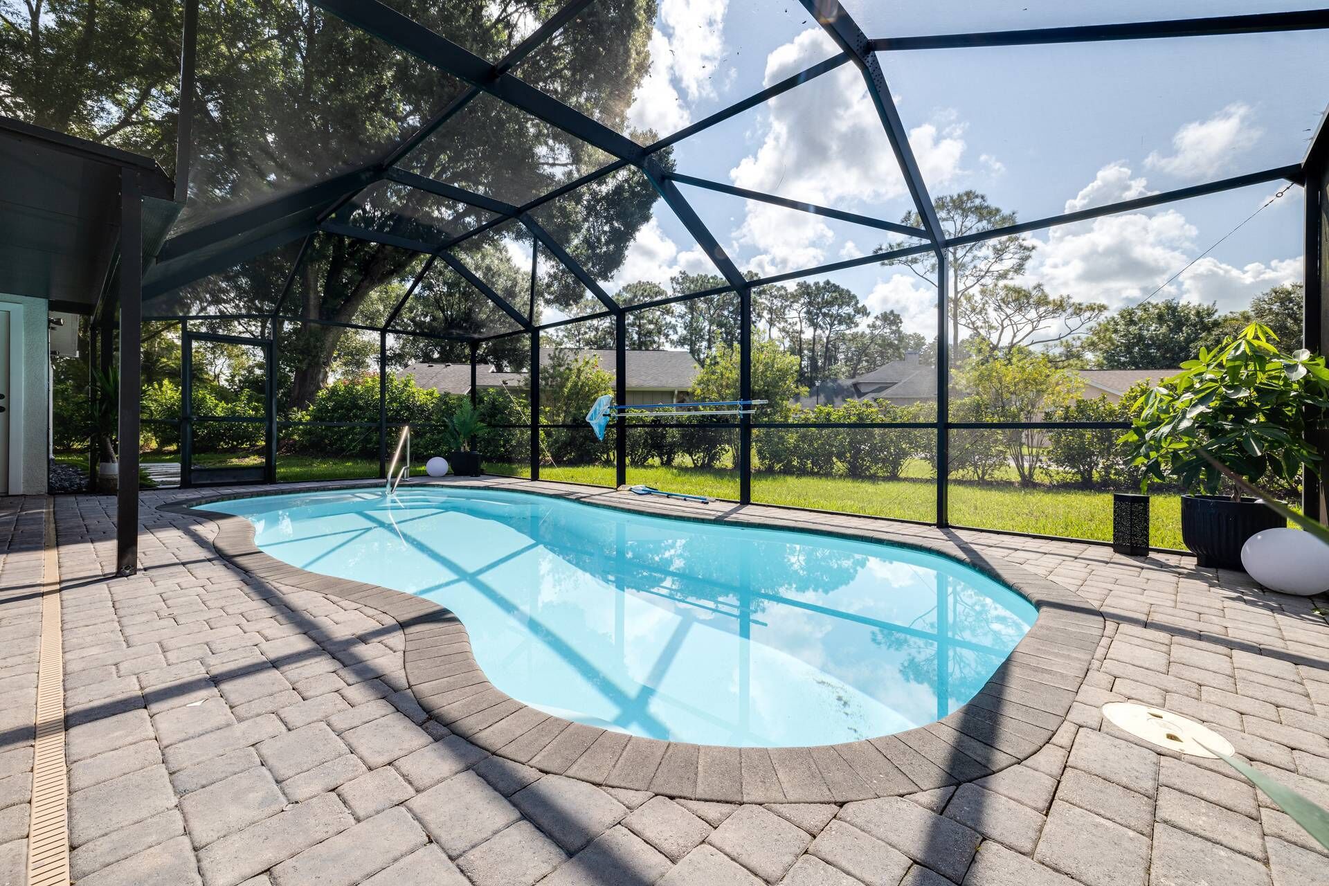 Una piscina interior amb una vista clara del verd circumdant i una zona coberta amb una estructura metàl·lica.