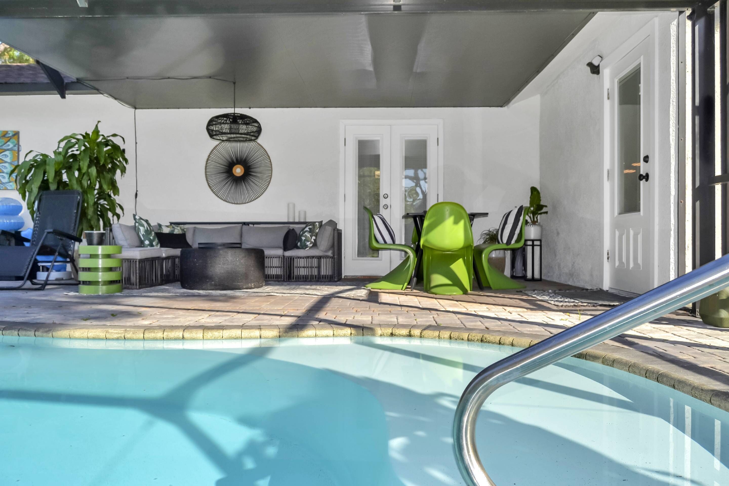 A pool area with a lounge chair, a sofa, and a fan on the wall.