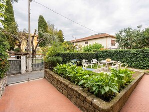 Une terrasse avec un mur en pierre, des chaises blanches et une table.
