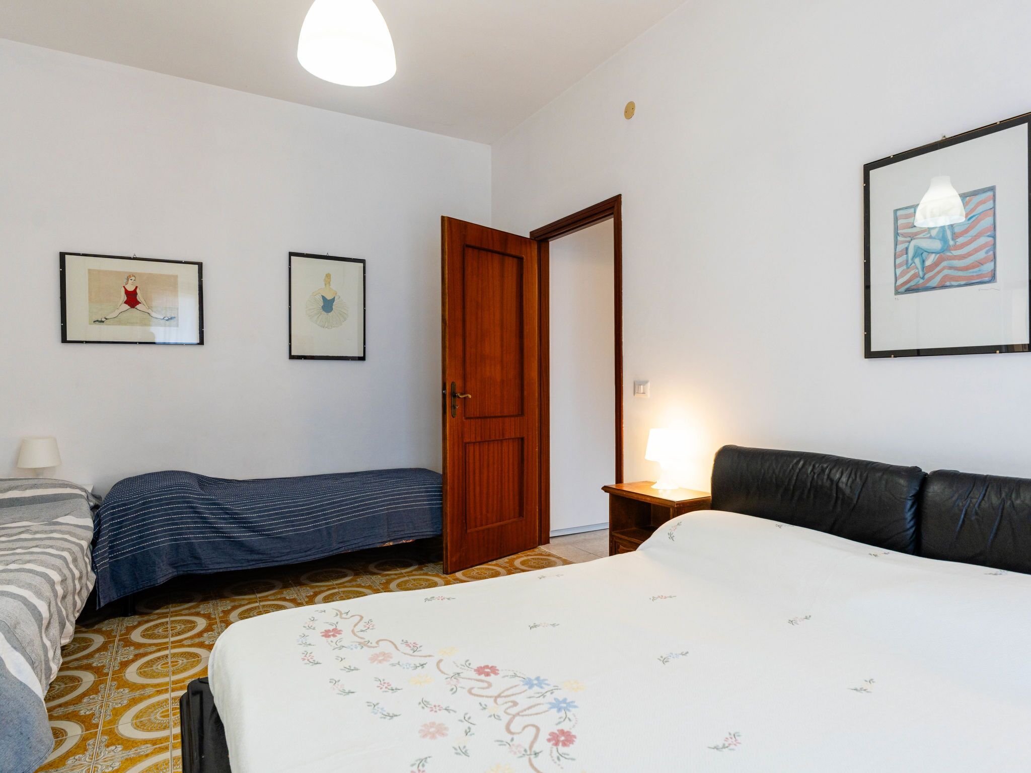 Ein Hotelzimmer mit einem Bett, zwei Nachttischen, einem Sessel und einer Tür.