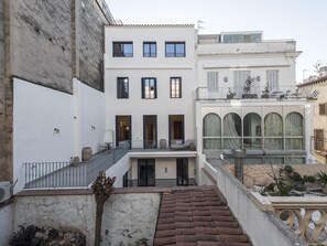 Un edificio de varios pisos con un patio central, que presenta una escalera que conduce a un nivel superior con un balcón.