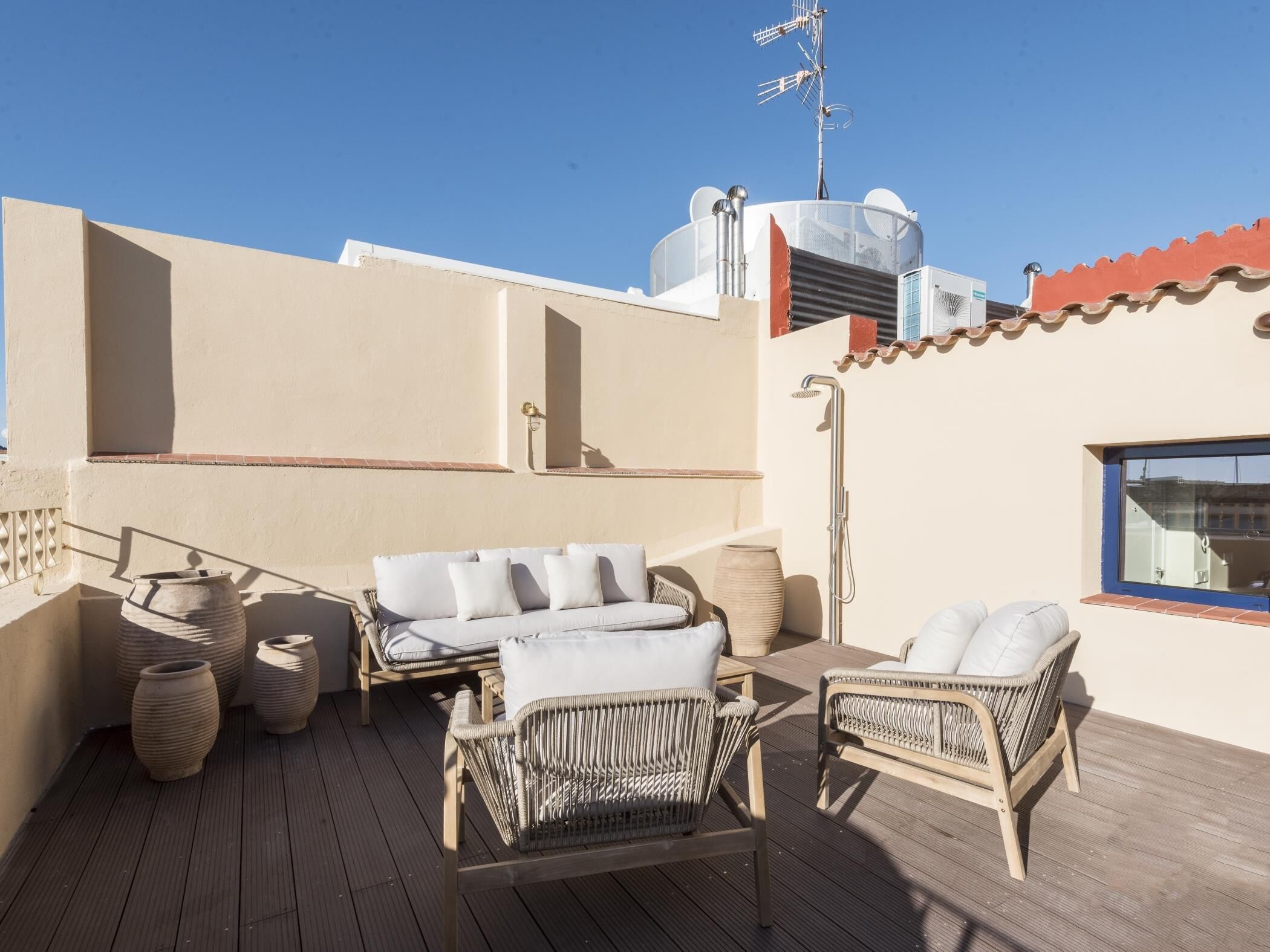 Una terraza en la azotea con mobiliario de mimbre, una fuente de agua y una antena parabólica.