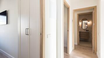 Un pasillo con suelo de madera, paredes blancas y una puerta de madera con pomo.