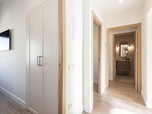 Un pasillo con suelo de madera, paredes blancas y una puerta de madera con pomo.