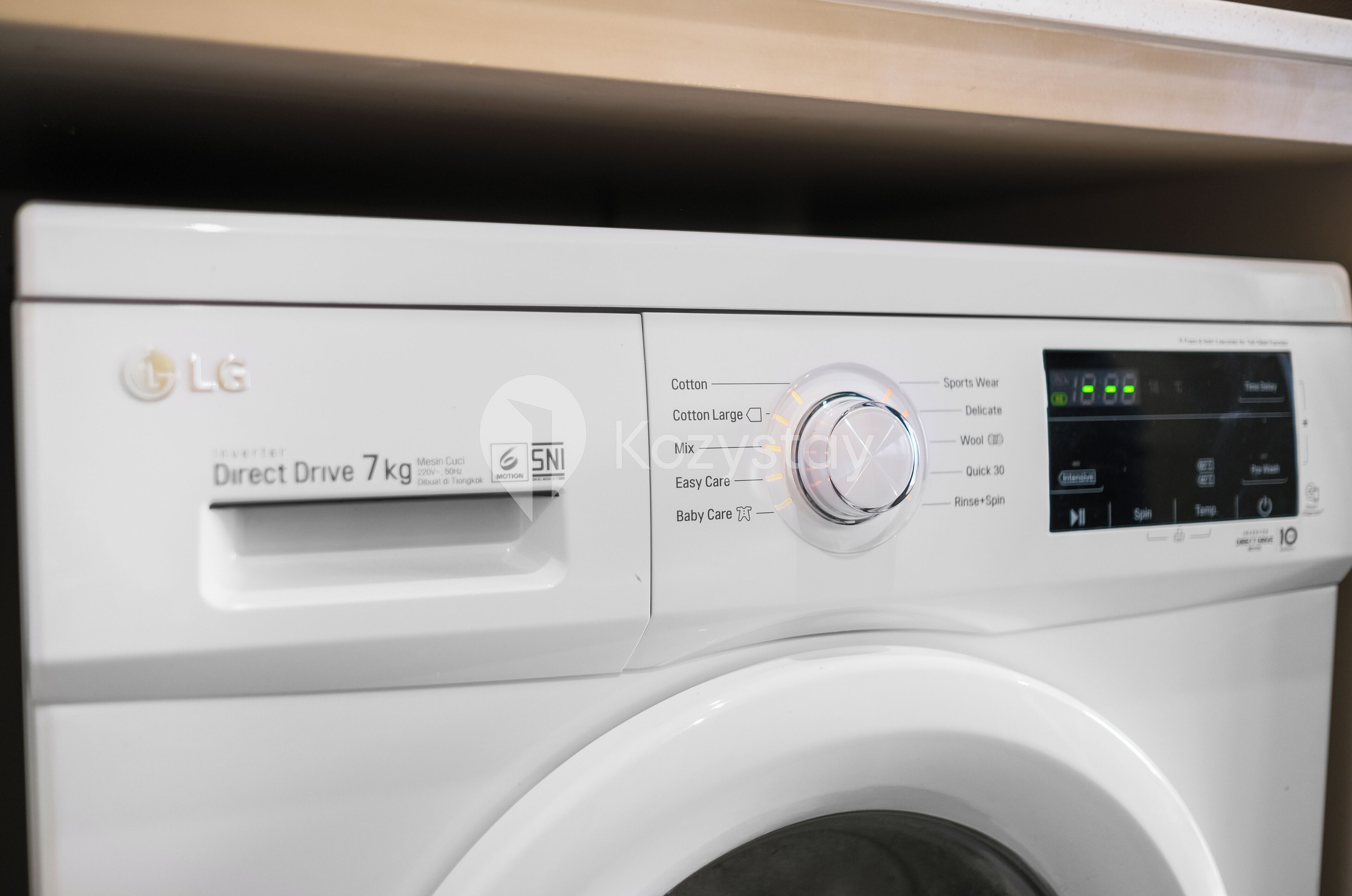 A front view of an LG Direct Drive 7kg washing machine with a control panel displaying various settings.
