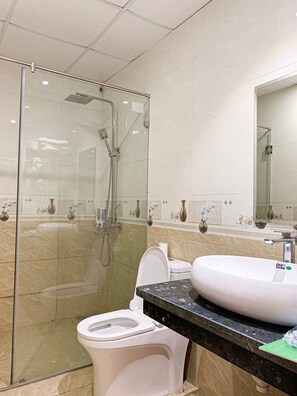 A modern bathroom with a glass-enclosed shower, a toilet, and a sink with a marble countertop. - An Hung 2 Hotel Hai Tien -BAY LUXURY (Hoang Hoa)