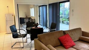 A modern living room with a brown sofa, a red pillow, and a dining area with a table and chairs. - Private Studio Retreat (Highland Park)