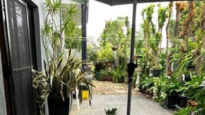 An outdoor patio with a round glass table and two chairs, surrounded by potted plants and a gravel floor. - Private Studio Retreat (Highland Park)