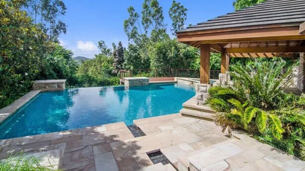 A swimming pool with a wooden pergola and stone steps, surrounded by lush greenery. - Private Studio Retreat (Highland Park)