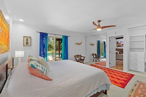 Un dormitorio con cama, ventilador de techo, armario y vistas al exterior.