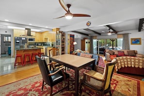 Amplia sala de estar con mesa de comedor, sillas, un sofá y una cocina al fondo.