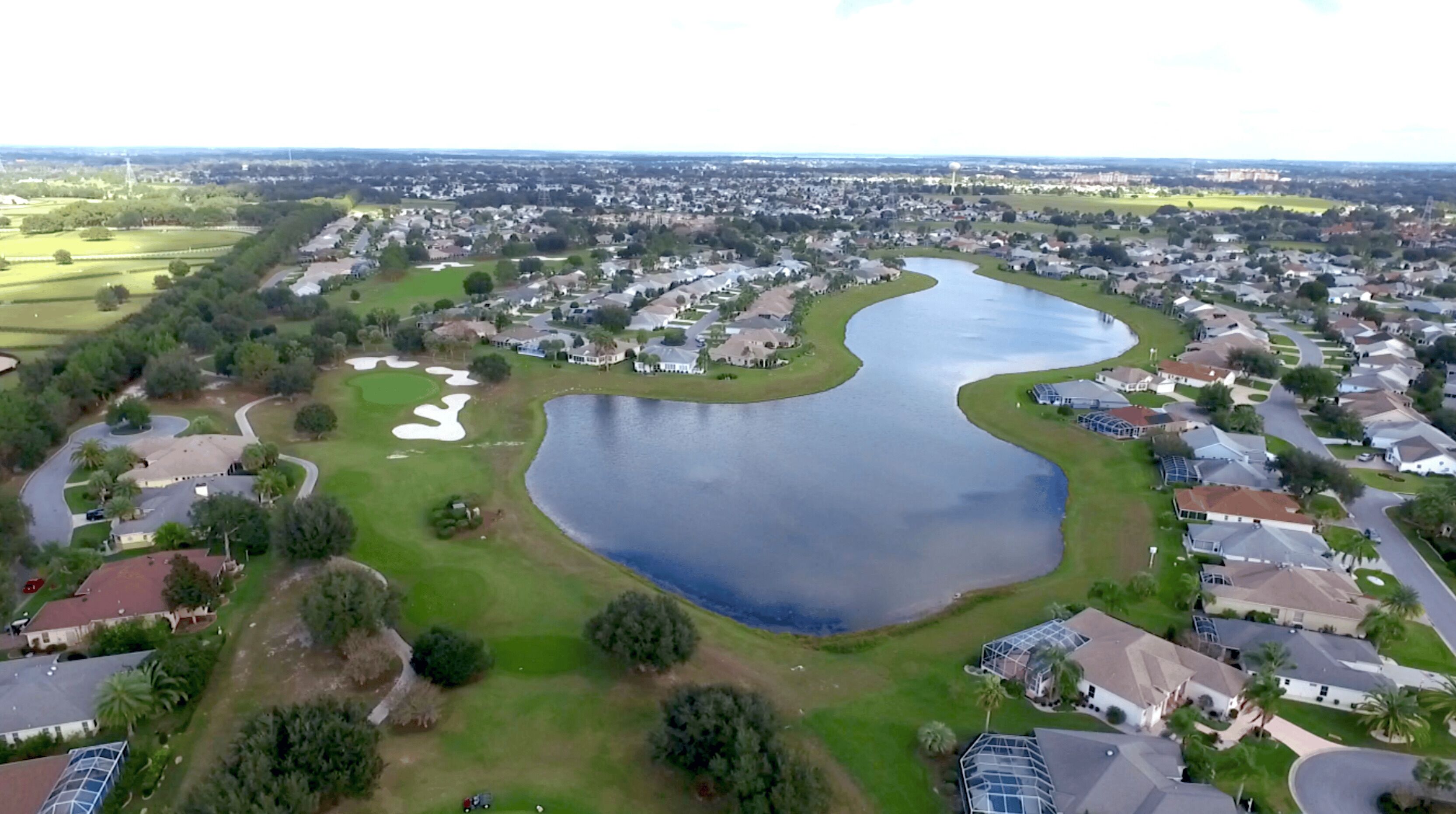 An aerial view of a residential area with a large lake, surrounded by houses and greenery.