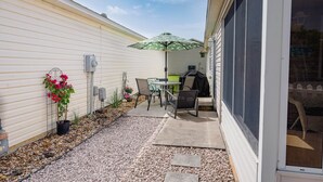 A patio with a table and chairs, a grill, and a potted plant.