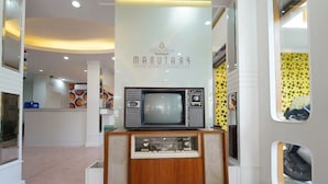 A retro-styled room with a vintage television set on a wooden cabinet, a modern ceiling with recessed lighting, and a wall with circular patterns. - Happy Live Quest Hotel  (Bangkok)