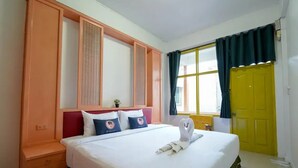 A hotel room with a bed, a nightstand, a window with curtains, and a yellow door. - Happy Live Quest Hotel  (Bangkok)