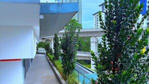 Un edificio moderno con un lungo e stretto corridoio fiancheggiato da piante e una ringhiera in vetro con vista sulla città.