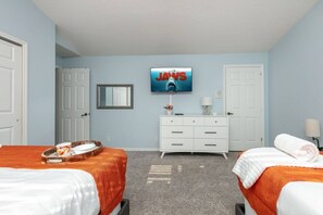 Una habitación de hotel con dos camas, un televisor en la pared, un aparador y un espejo.