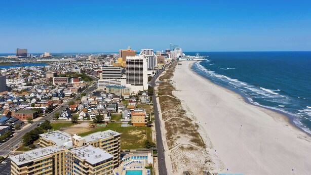 Un paysage urbain côtier avec une plage, des immeubles de grande hauteur et un ciel bleu dégagé.