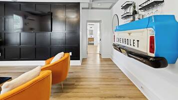 A modern interior with a black wall panel, a Chevrolet car model, and orange chairs.