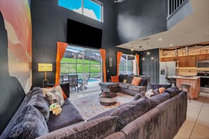Uma sala de estar moderna com sofás escuros, uma mesa de centro e vista para um quintal.