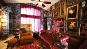 Un salón acogedor con pared de piedra, chimenea, sofá rojo y una colección de cuadros enmarcados en la pared.