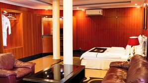 A hotel room with a bed, a sitting area with a coffee table, and a wardrobe with a clothing rack. - Galaxy Hotel (Kigali)