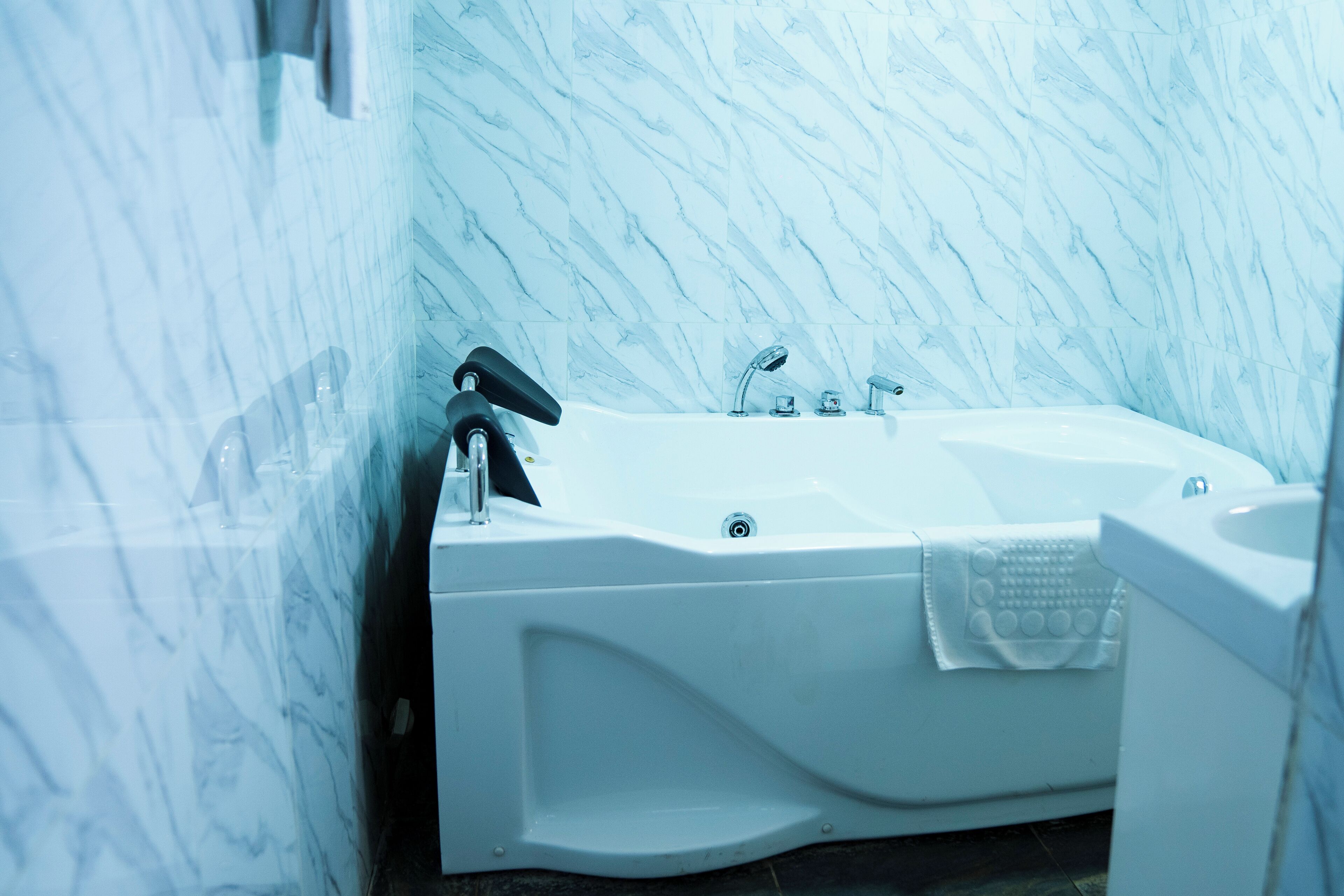 A modern bathroom with a white bathtub, a handheld showerhead, and a sink.