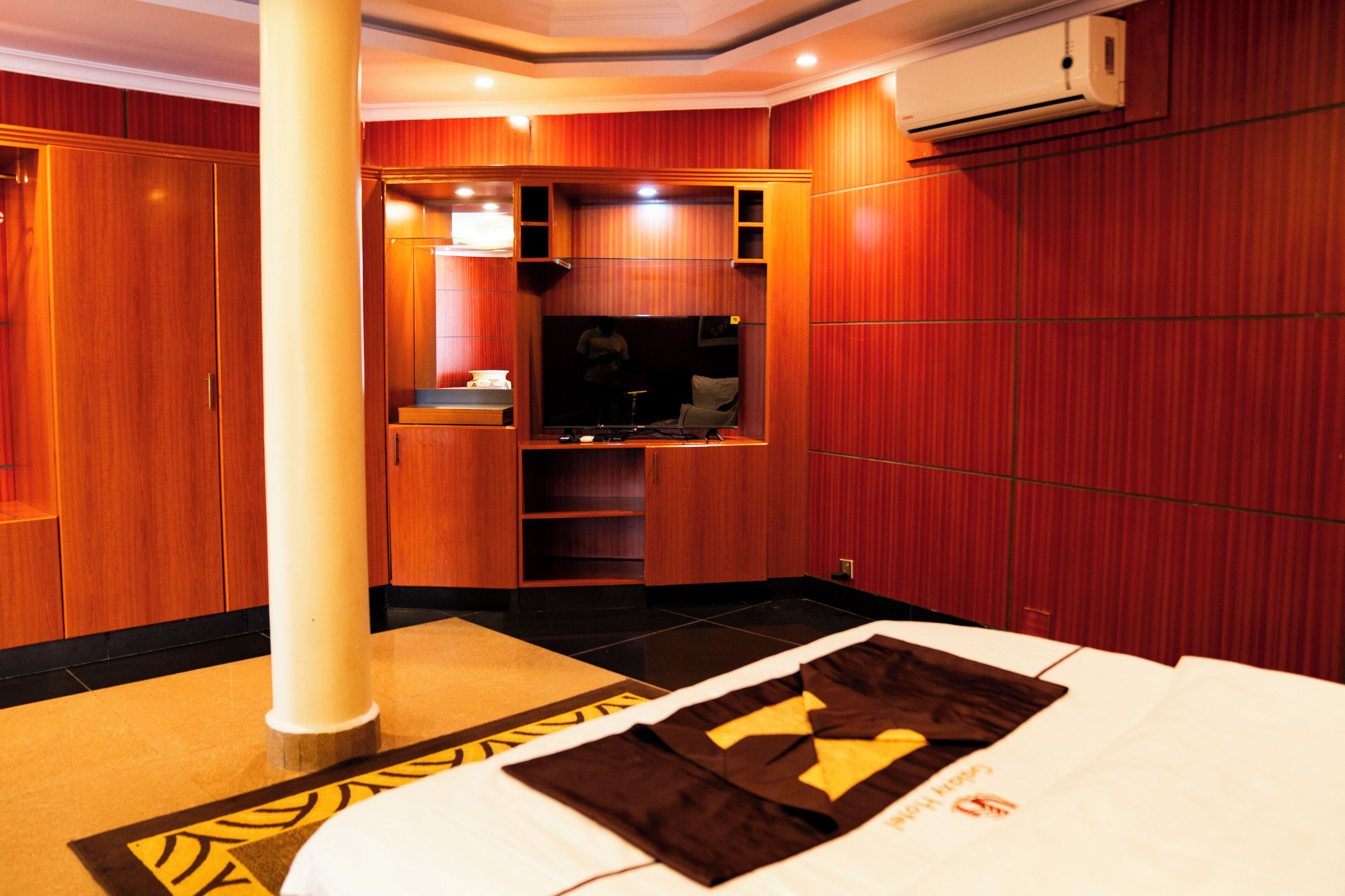 Una habitación de hotel con cama, tocador, espejo, televisor y armario.