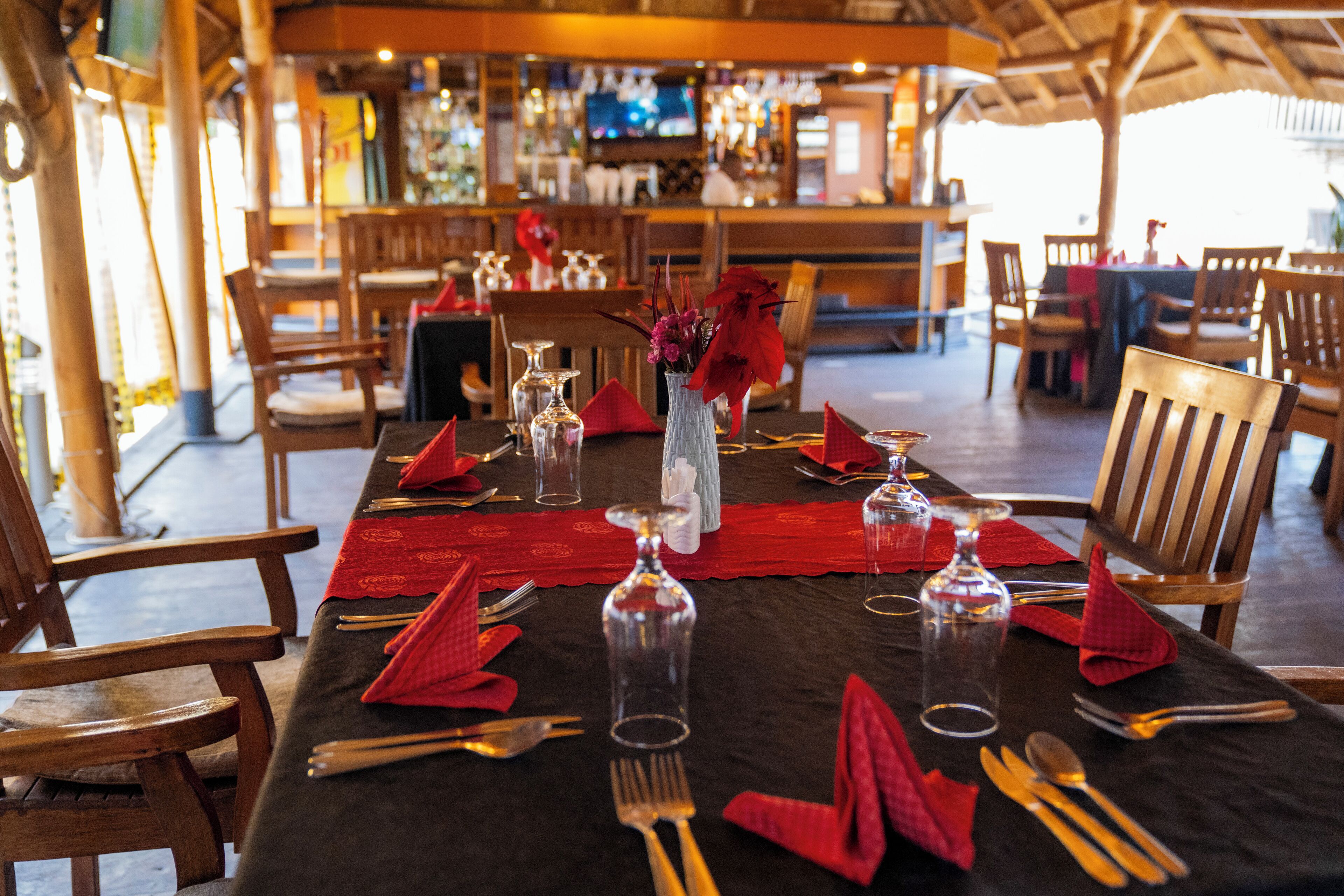 A restaurant setting with a table set for dining, chairs, and a bar in the background.