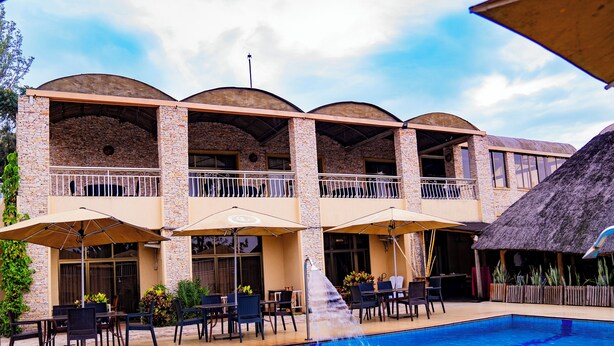 A hotel with a pool, outdoor seating, and a thatched-roof structure. - Galaxy Hotel (Kigali)