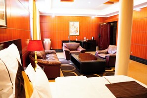 A hotel room with a large bed, two sofas, a coffee table, and a desk. - Galaxy Hotel (Kigali)