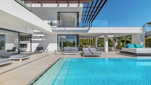 Relax in a serene outdoor setting with a pool, comfortable lounge chairs, and a dining space.