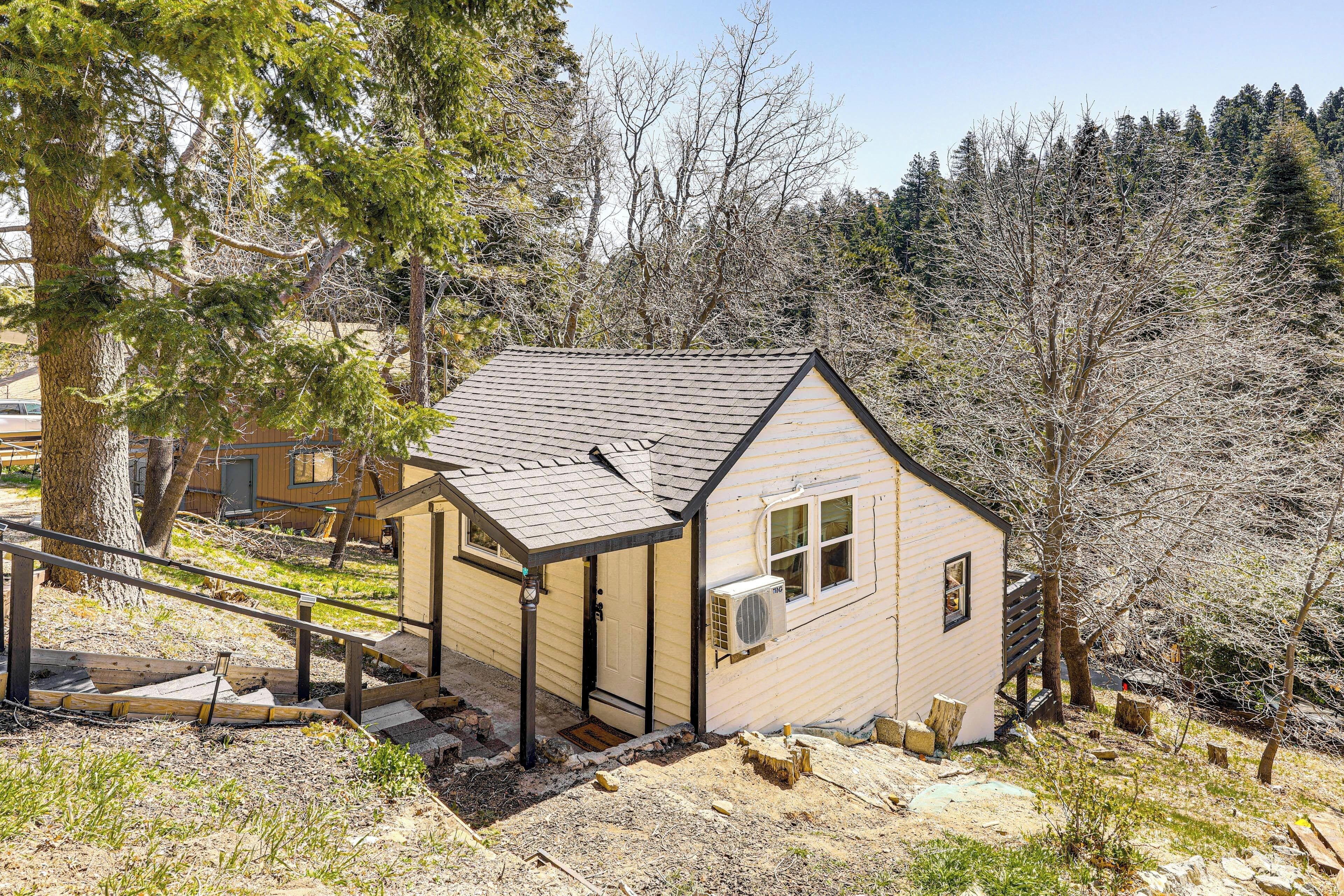 A small, single-story cabin with a sloped roof, a front porch, and a visible air conditioning unit.