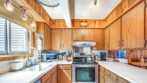 Una cocina moderna con armarios de madera, electrodomésticos de acero inoxidable y un ventanal grande.