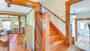 Una scala in legno con corrimano che conduce a una stanza con una parete verde e un divano.