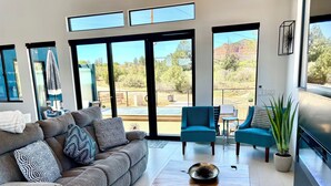 A modern living room with a grey sofa, a wooden coffee table, and a blue armchair. - 2 King Ensuites Elevated Views Spa Amenities at Sedona Sky (Sedona)