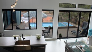 A modern dining area with a large table, chairs, and a view of an outdoor swimming pool through large windows. - 2 King Ensuites Elevated Views Spa Amenities at Sedona Sky (Sedona)