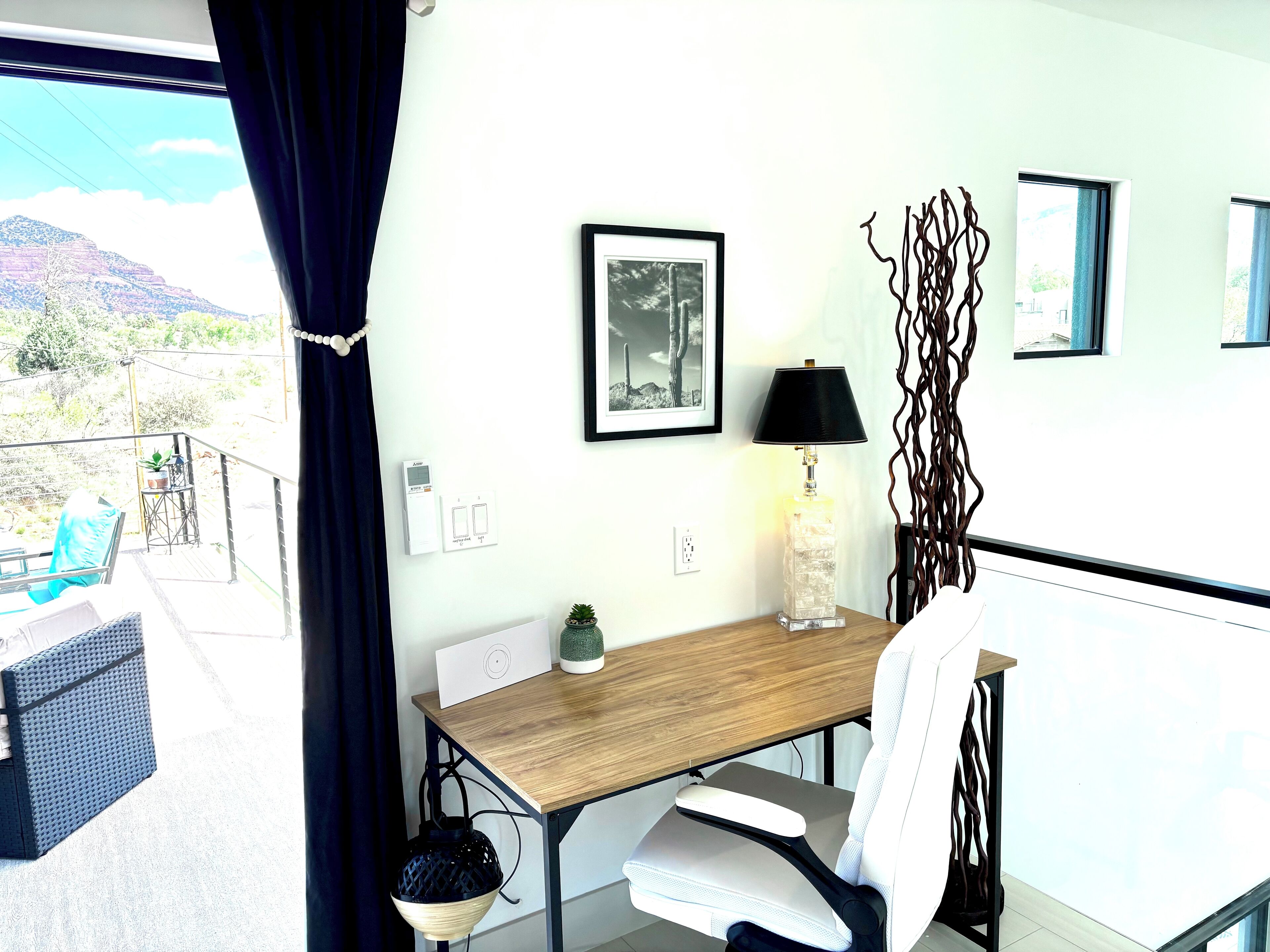 A modern room with a wooden desk, a white chair, a black lamp, and a decorative wall piece.
