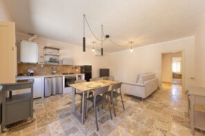 A modern kitchen with a dining area, a sofa, and a TV.