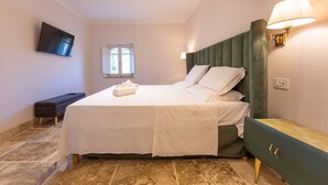 Une chambre à coucher avec un lit, une table de chevet, une lampe, un téléviseur et une fenêtre.