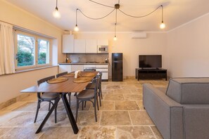 Una cucina moderna con tavolo, sedie, divano e televisore.