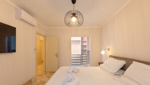 A hotel room with a bed, a TV, a wardrobe, and a hallway leading to another room. - Borgo Ariano 4 – Apartment with pool (Volterra)
