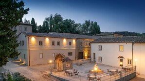 A courtyard with stone walls, outdoor seating, and a stone fountain. - Borgo Ariano 6 – Apartment with pool (Volterra)