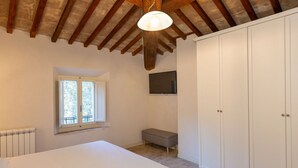 A bedroom with a bed, a window, a television, and a wardrobe. - Borgo Ariano 6 – Apartment with pool (Volterra)