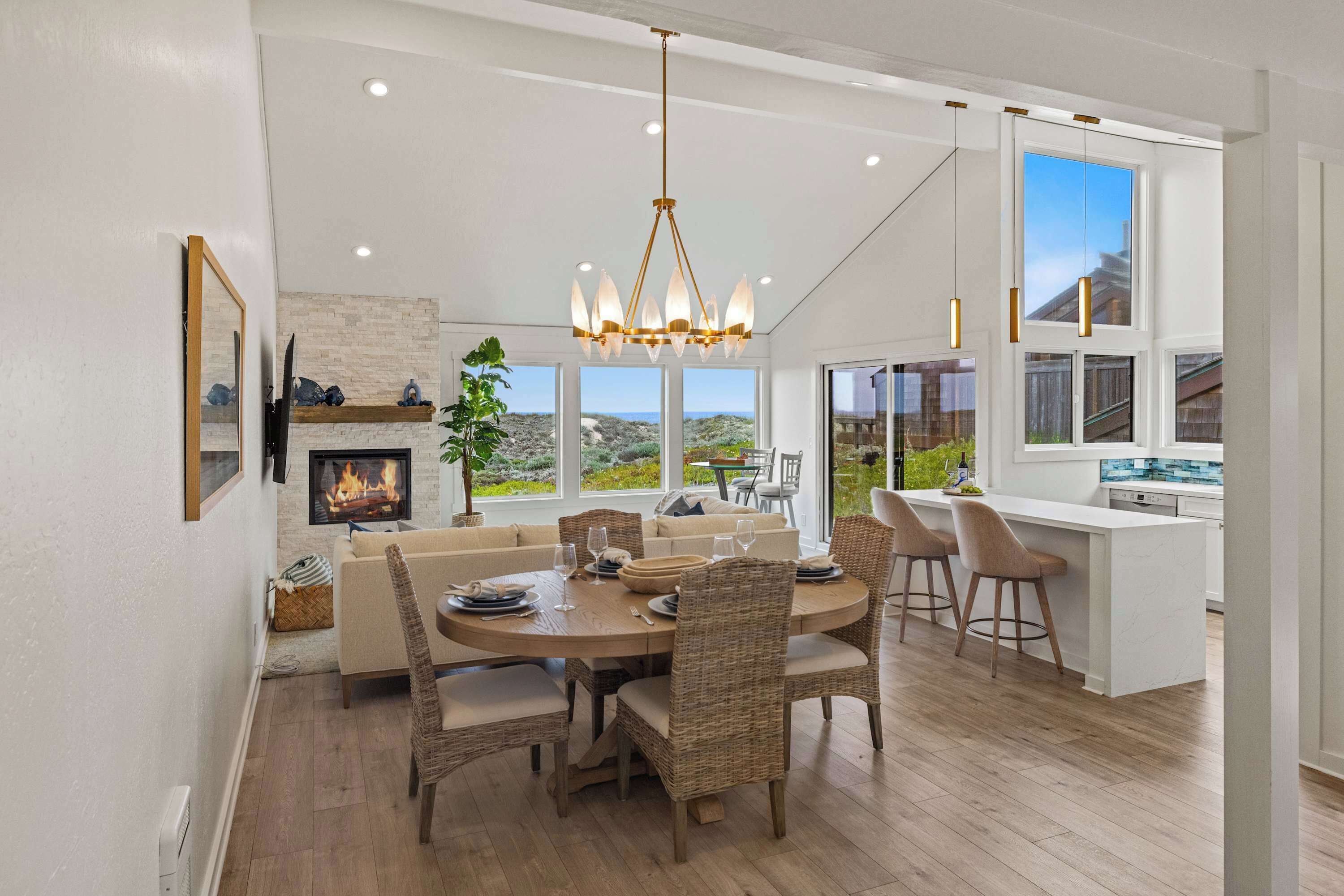 A modern kitchen with a large island, a dining area with wicker chairs, and a fireplace.